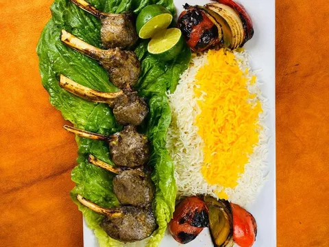 Rack of lamb kabob at Shamshiri Grill in Westwood, Los Angeles, plated with saffron-topped basmati rice and grilled tomato, onion and pepper on romaine