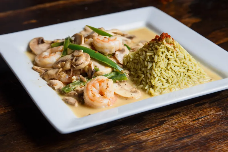 Tequila Museo Mayahuel's Camarones Moctezuma al Tequila — sautéed shrimp with mushrooms and green beans in a light tequila cream sauce alongside a mound of green rice on a white plate