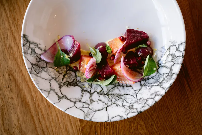 Rasa's beets salad plated on a marbled bowl — fresh beets, citrus, pomegranate and creamy yoghurt