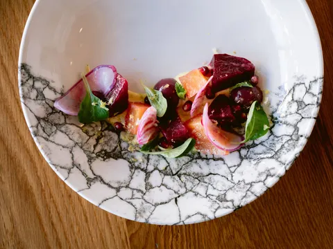 Rasa's beets salad plated on a marbled bowl — fresh beets, citrus, pomegranate and creamy yoghurt