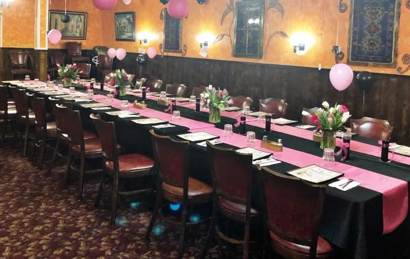 Casa Mexico's Fairview banquet room in Boise set with long tables in black cloths and pink runners, fresh tulips and pink balloons under warm orange walls