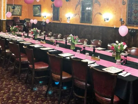 Casa Mexico's Fairview banquet room in Boise set with long tables in black cloths and pink runners, fresh tulips and pink balloons under warm orange walls