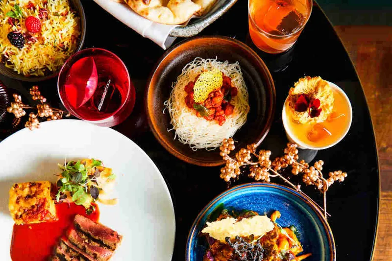 Spread of modern Indian dishes with naan, jewelled biryani rice, plated tikka and cocktails at Farzi Café, Bellevue
