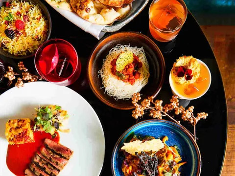 Spread of modern Indian dishes with naan, jewelled biryani rice, plated tikka and cocktails at Farzi Café, Bellevue