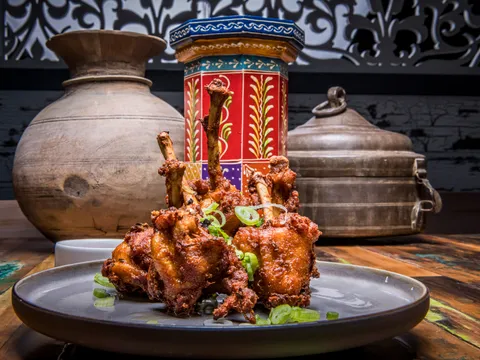 Plate of spiced chicken lollipops garnished with scallions at Bombay Street Kitchen