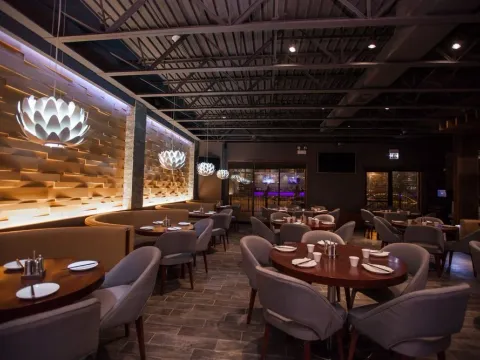 Dining room with lotus-shaped pendant lights and wood tables at Dolo Restaurant & Bar in Chicago's Chinatown