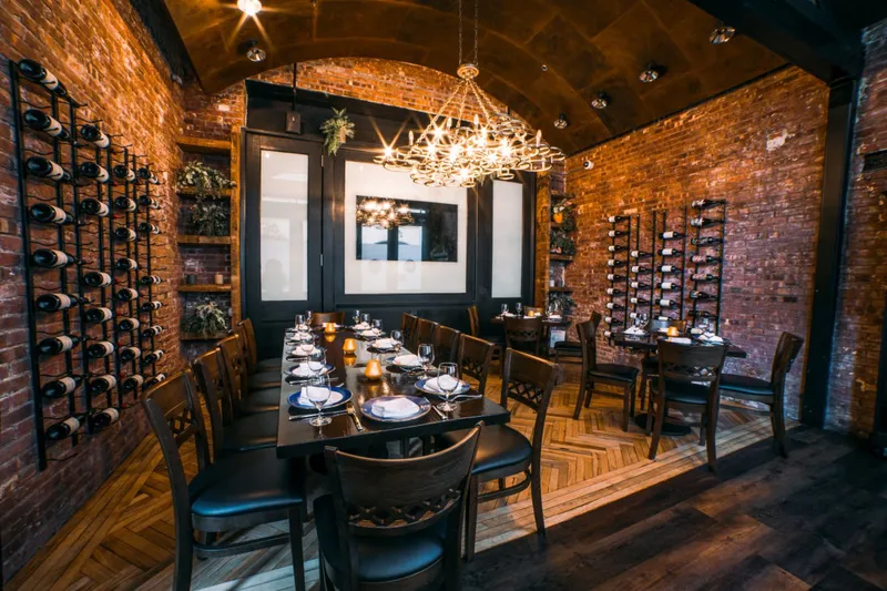 Exposed-brick private dining room with a long set table and wine racks at Paisley in Tribeca