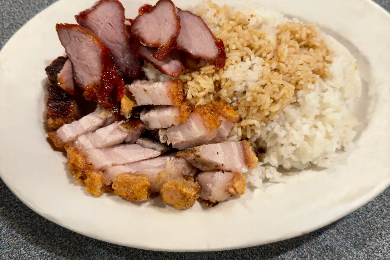 A BBQ combination rice plate with sliced char siu barbecue pork and crispy roast pork belly over rice at Kau Kau BBQ