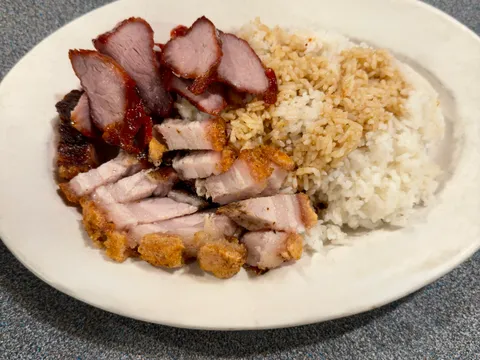 A BBQ combination rice plate with sliced char siu barbecue pork and crispy roast pork belly over rice at Kau Kau BBQ