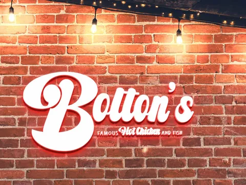 Illuminated Bolton's Famous Hot Chicken and Fish sign mounted on the exposed brick wall inside the restaurant