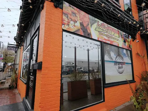 Orange brick corner exterior of Merengue House Restaurant & Bar strung with patio lights