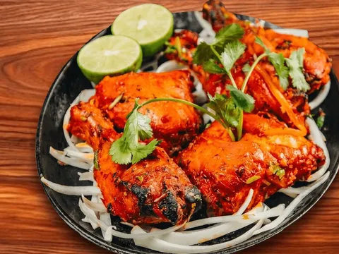 Plate of tandoori chicken garnished with cilantro and lime over sliced onions at Bombay House in Tempe.