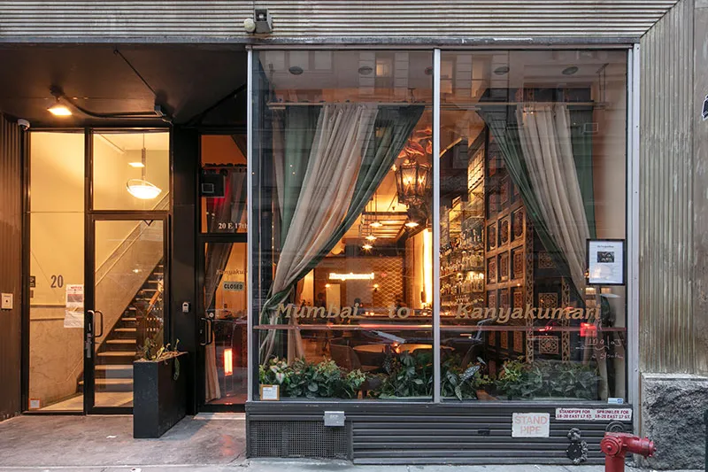 Evening view of Kanyakumari's Union Square storefront on East 17th Street, with 'Mumbai to Kanyakumari' lettering across the front windows and a warmly lit dining room inside