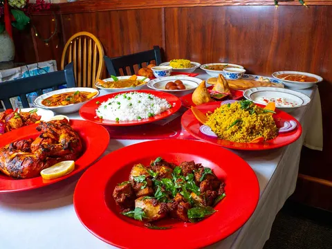 Table laid with curries, rice and appetizers on red plates at Chili's South Indian Cuisine
