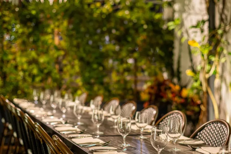 Pasjoli garden dining table set beneath glass pendant lights and greenery