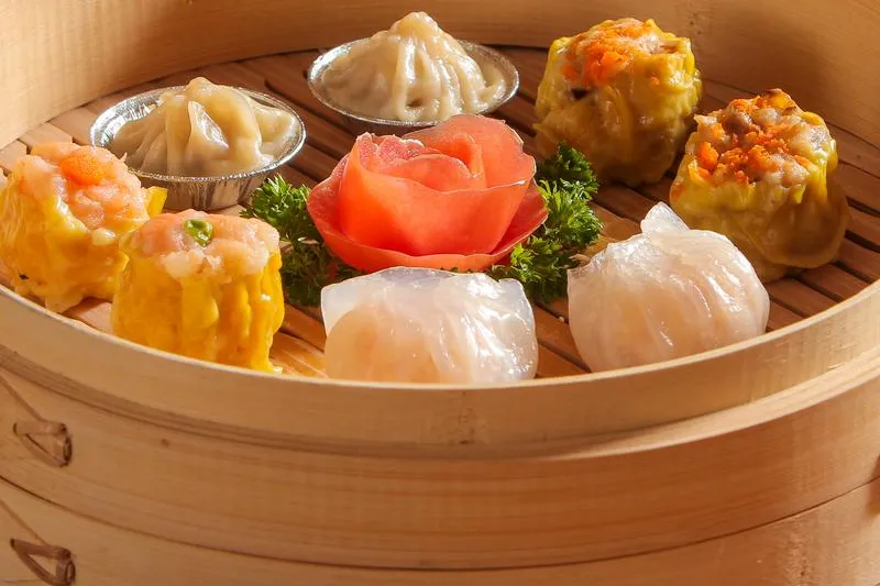 An assortment of steamed dim sum — shumai, har gow and soup dumplings — in a bamboo steamer basket at Fung's Kitchen in Houston