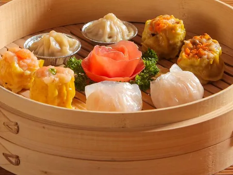 An assortment of steamed dim sum — shumai, har gow and soup dumplings — in a bamboo steamer basket at Fung's Kitchen in Houston